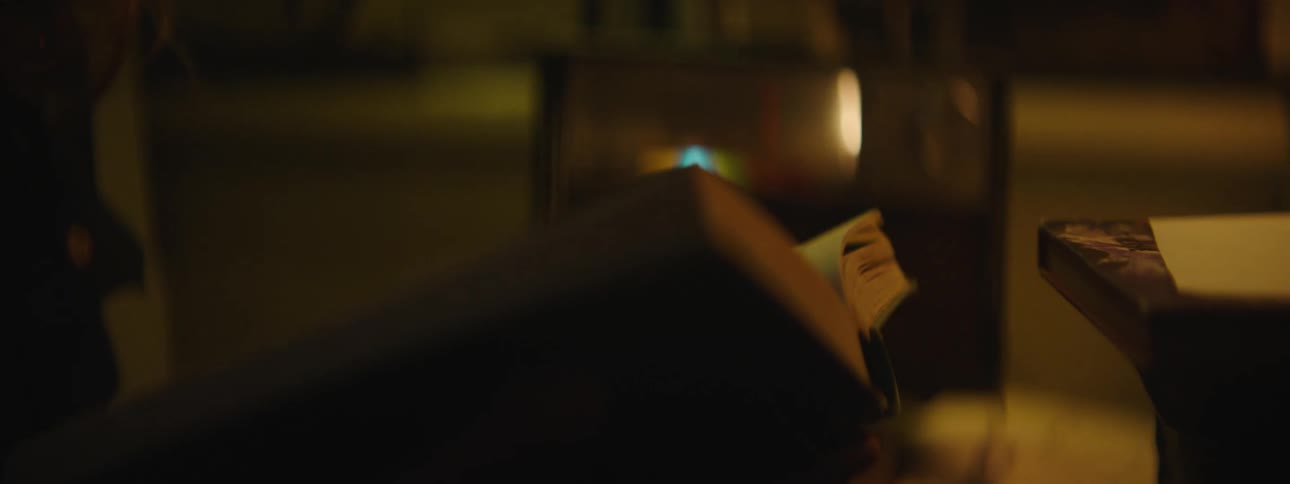 Close up of the hands of a woman turning the pages of a big book on a dimly lit room