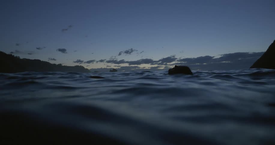Woman floating on ocean at dusk