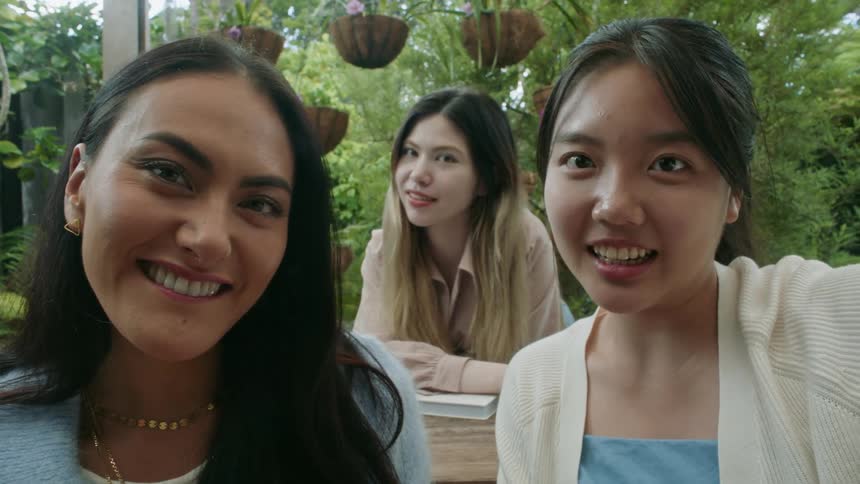 Three women smile and laugh as they all pose together for a selfie