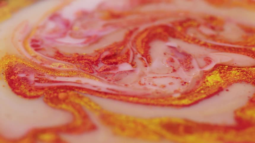 Color spices swirl in a bowl of milk