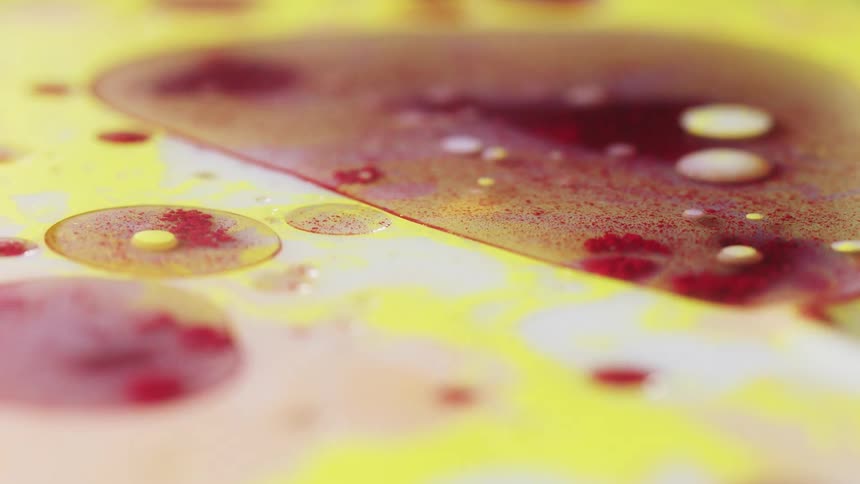 Reddish powder drops onto surface of multicolored liquid