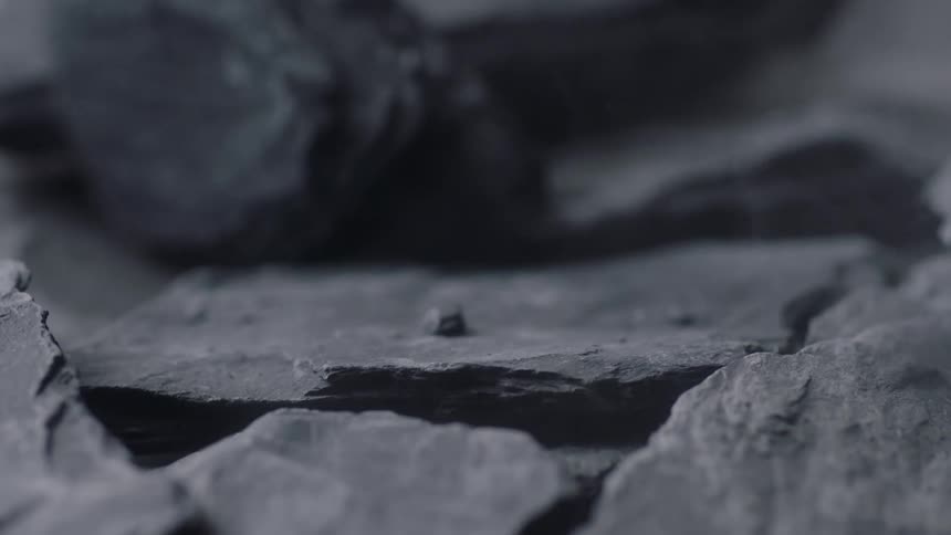 A heavy shard of stone falls forcefully onto a pile of other pieces