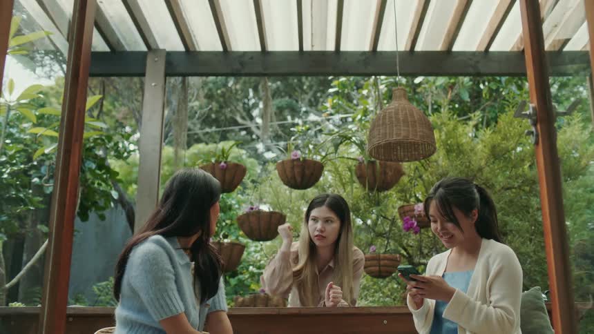 A trio of young women sit outside while socializing with each other