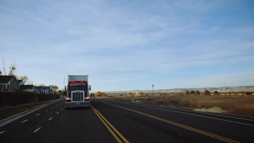 Traffic is driving on a rural highway at midday