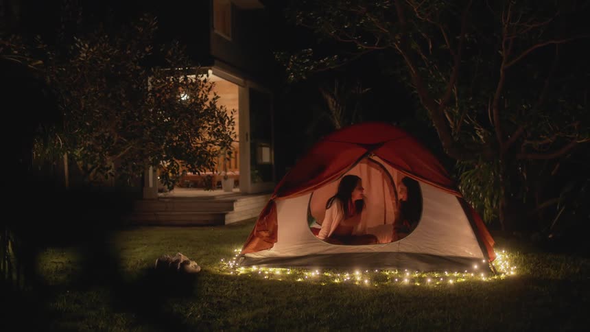 Two females are camping in a tent during the night time
