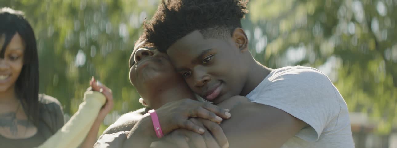 A boy hugs a woman on a sunny day
