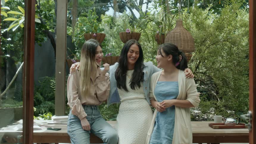 Three woman standing in front of a table outside laughing and smiling at one another