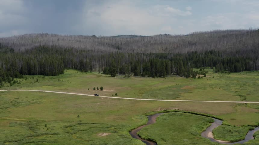 Aerial view of a car driving through a grassland rural area