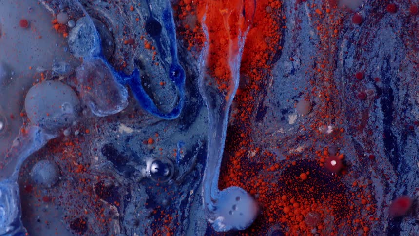 Close up of swirling bright red and blue liquid ink splashing around