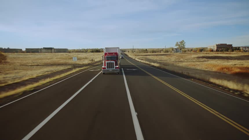 A semi truck is driving down the high way