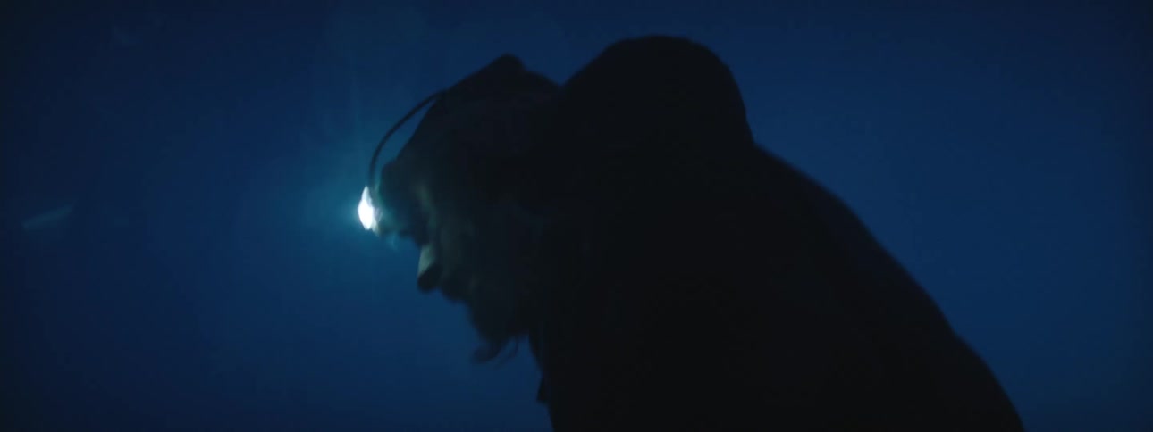 Silhouette of a man in the countryside hurriedly wearing a headlamp at night looking for something