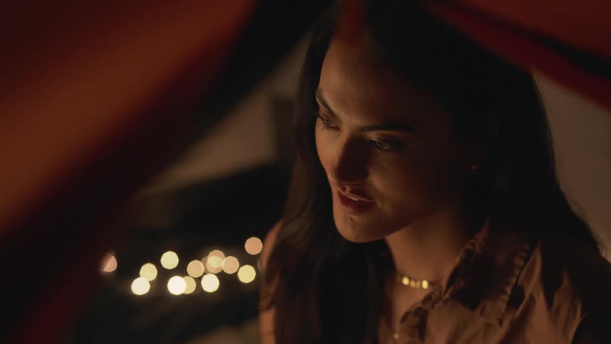 Woman smiles slowly at night indoors
