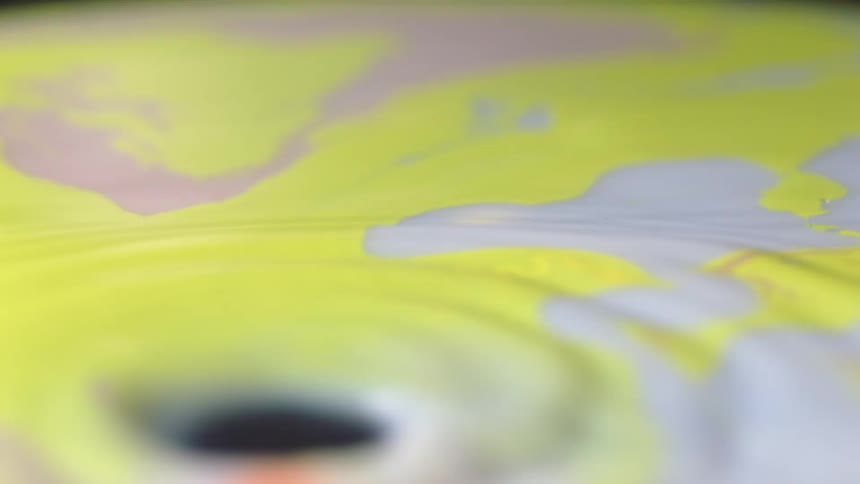 Yellow and white liquid paint swirling and rippling around