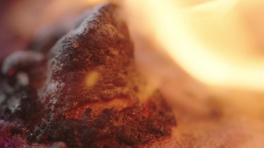 Flames waver and move as a charred substance bubbles and burns