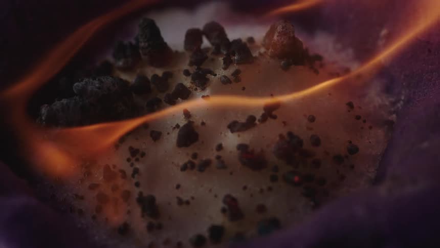 Close up of yellow flames burning and charring the surface of cotton candy