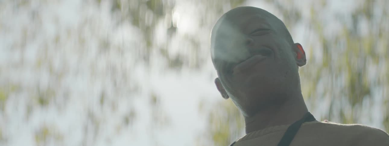 A man laughs under a tree during the day
