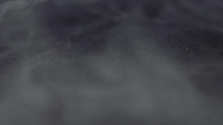 A close up of a grey cloth with steam rolling off of it