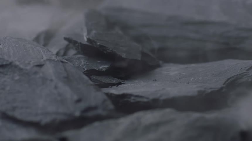 Close up of slates falling over a pile and shattering in small pieces and dust