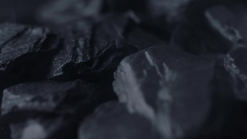 Pale vapor rises above textured dark gray stones