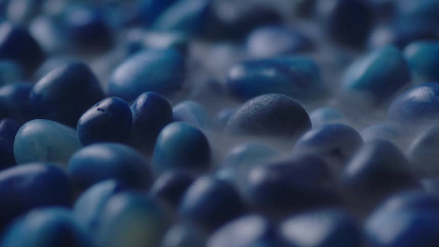 Pale vapor floats from blue pebbles