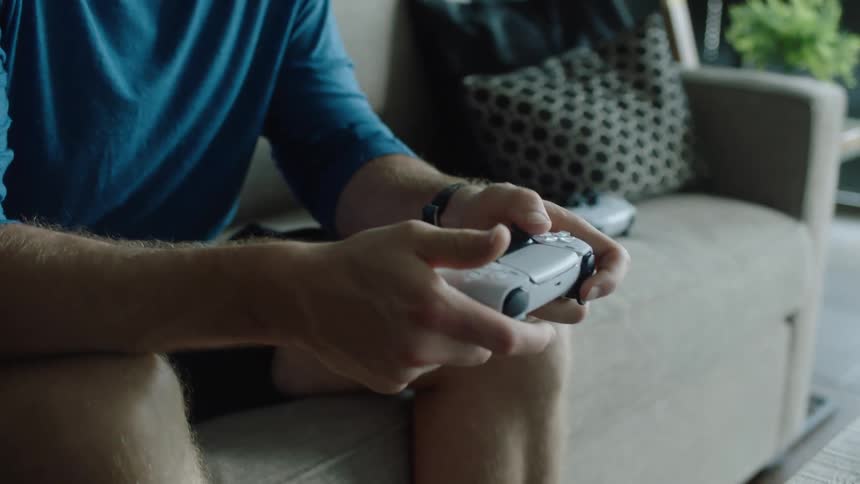 A man is playing video gaming while sitting on a couch
