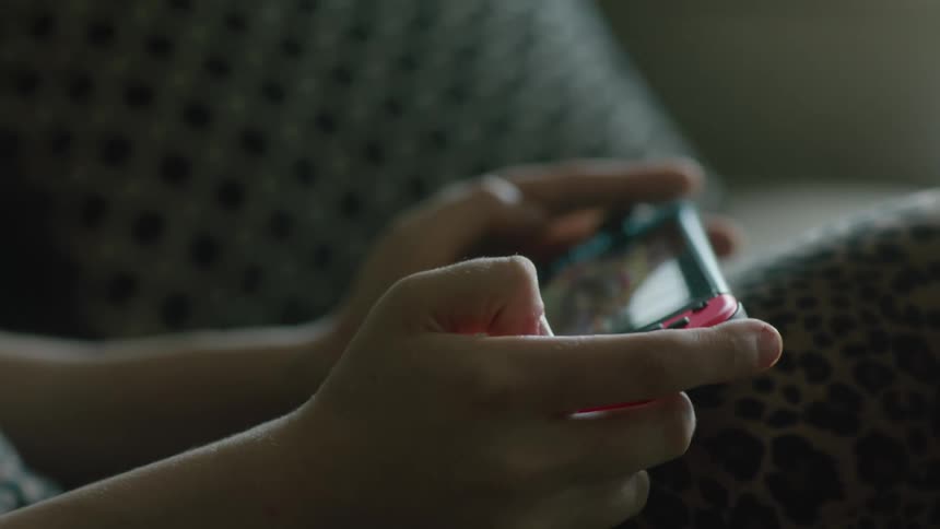 A close up of a person playing a hand held game using both hands