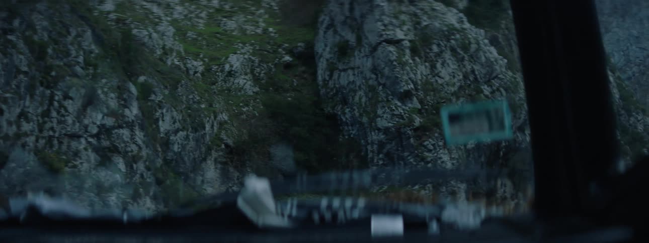 Point of view of a vehicle driving on a dangerous mountain road next to large rock cliffs