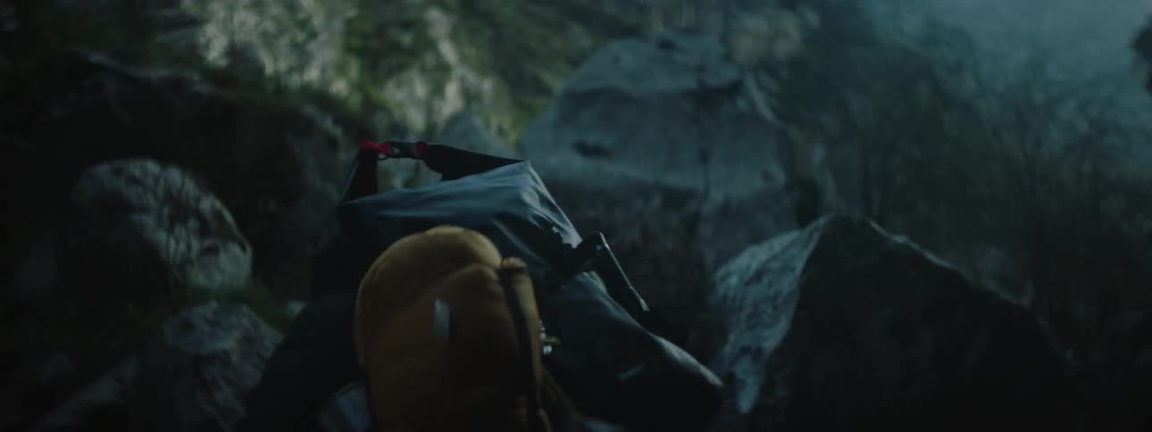 A man with hiking equipment on his back turning and walking up a mountain trail