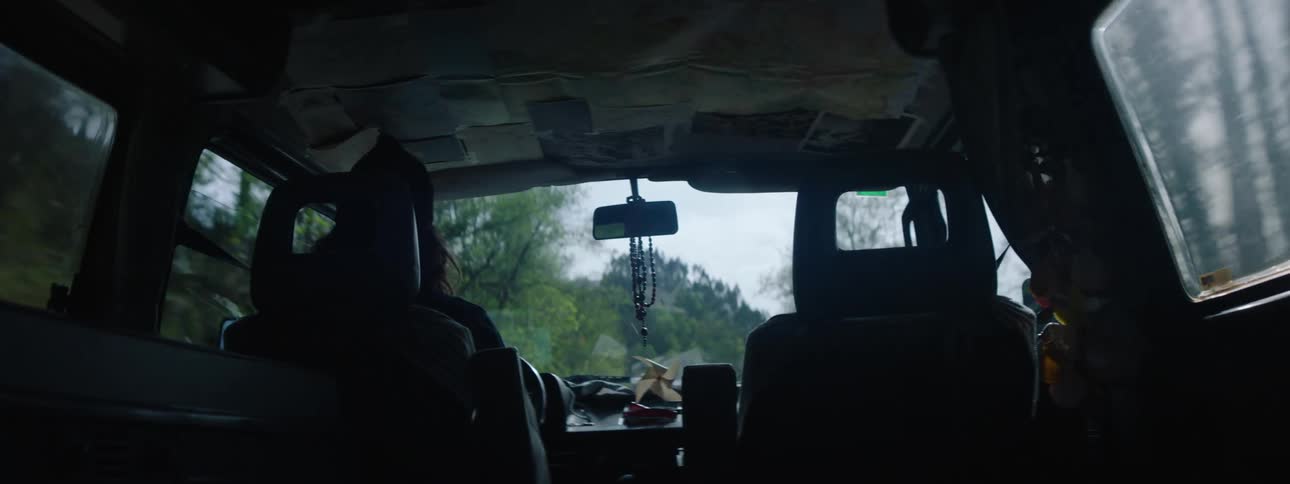 Long haired man drives a car on a road through the countryside at daytime