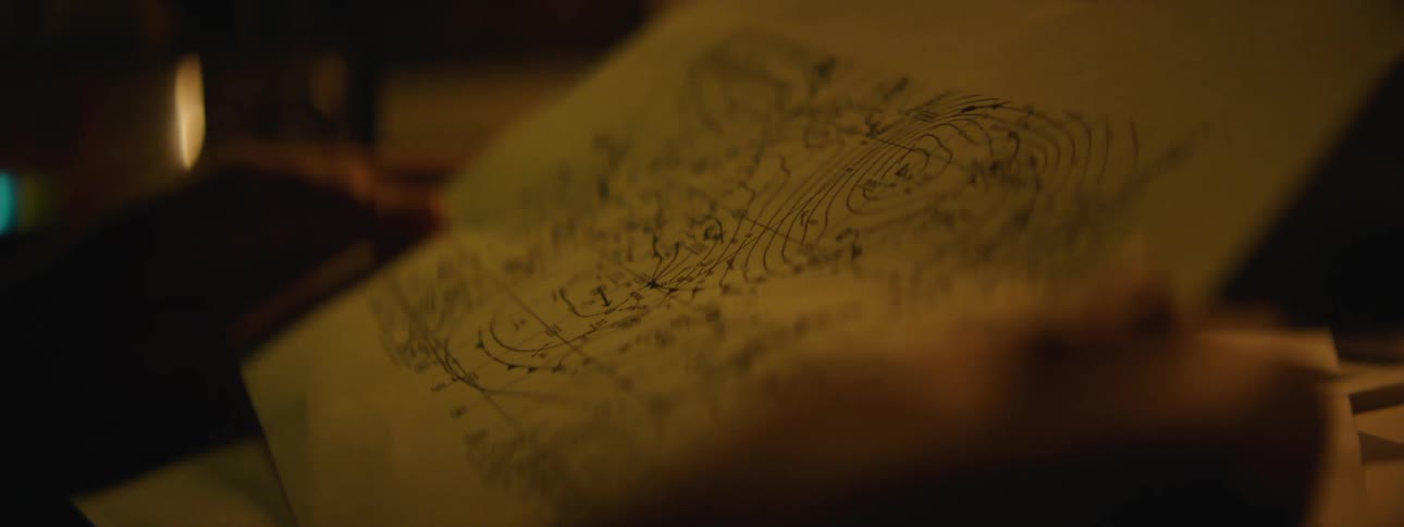 A man closely looks over a sketched drawing on paper