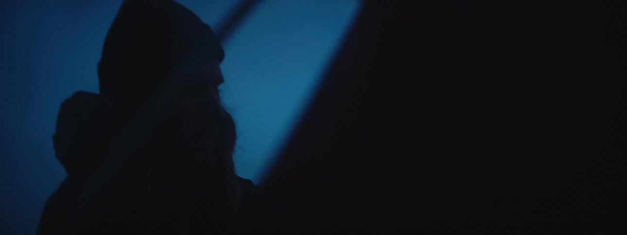Silhouette of a man wearing winter clothes assembling a tent at evening
