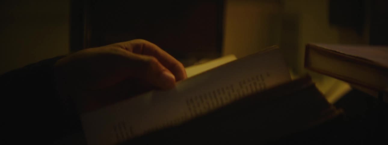 A person is reading a book while sitting indoors