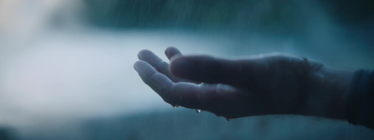 A persons hand being held out in the rain