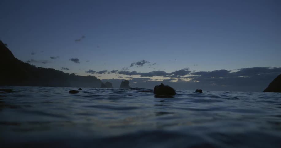 Rocks are floating in the ocean water at dusk
