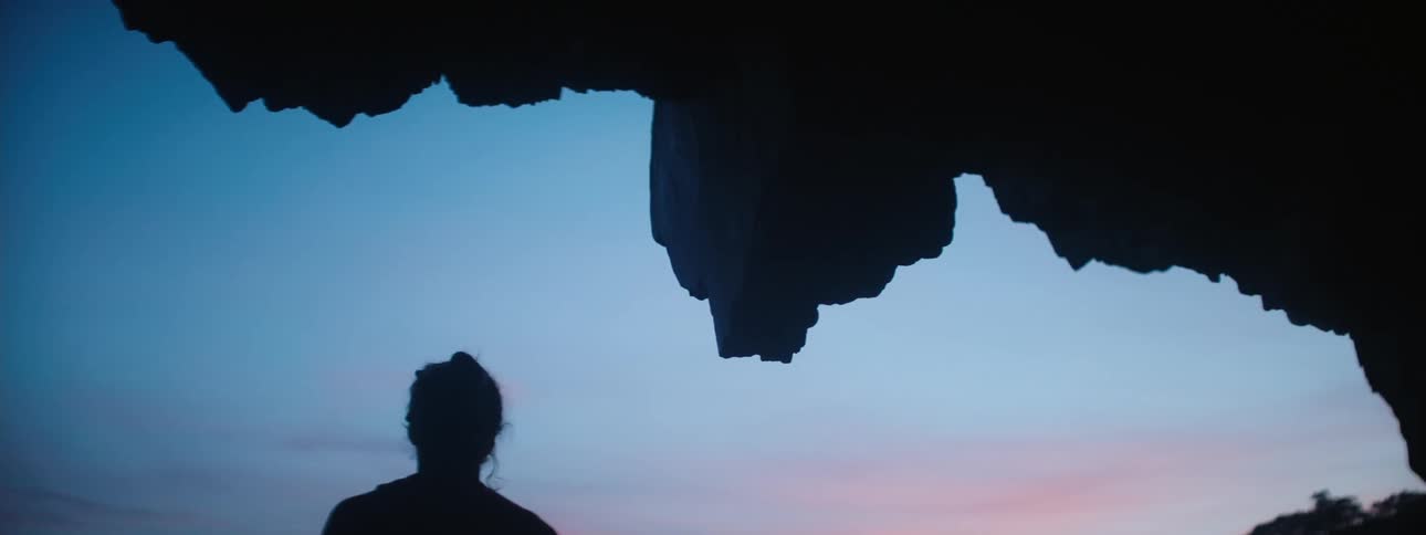 A woman walks from the cave