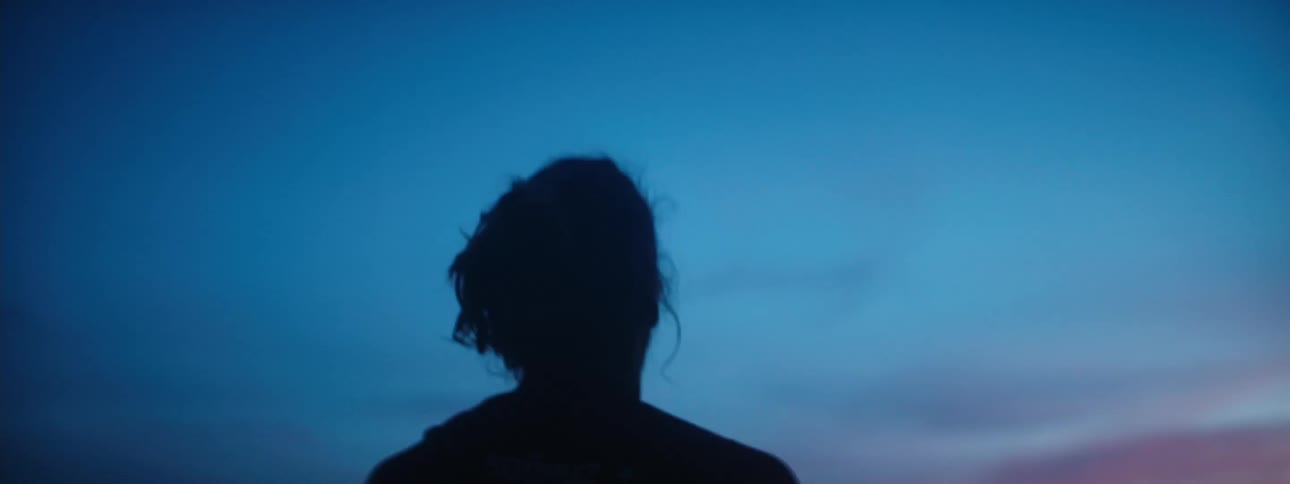 The silhouette of a person gazing up at the sky on a beach at sunset