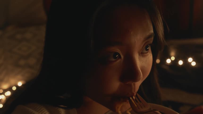 A woman is eating a bowl of food and sitting in a tent