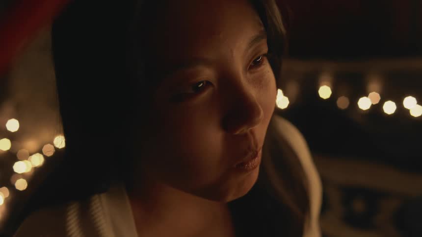 An up close of a womans face as she eats noodles with a fork and smiles nodding her head