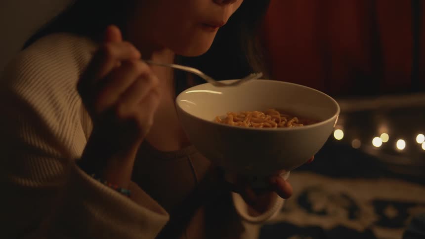 A woman eats noodles from a bowl