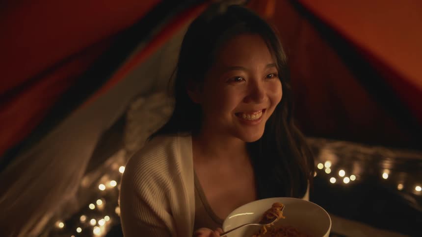 A young woman is eating food and is smiling