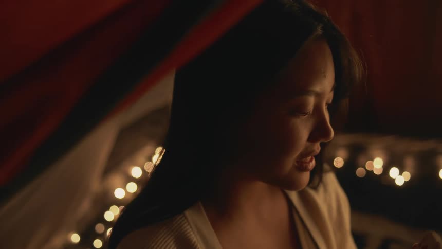 A woman is smiling and sitting inside of a tent
