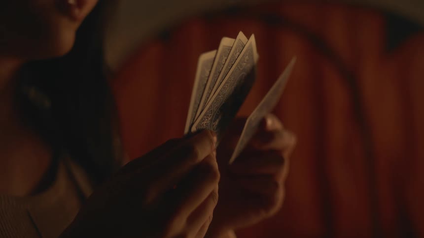A woman holding playing cards in her hands and taking one and removing it from her hands