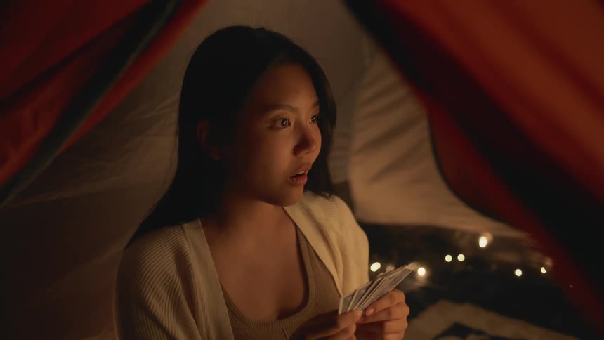 Woman playing cards in a tent