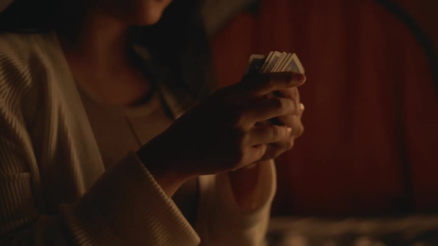 A young woman is playing cards inside of a tent