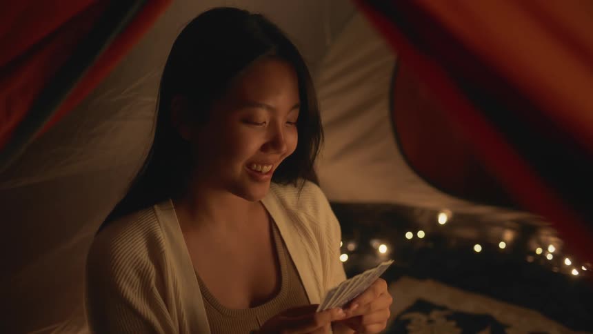 A woman is playing a card game while sitting in a tent