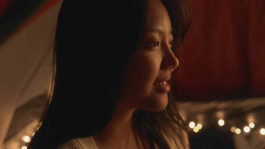 A asian woman talking to someone inside a tent