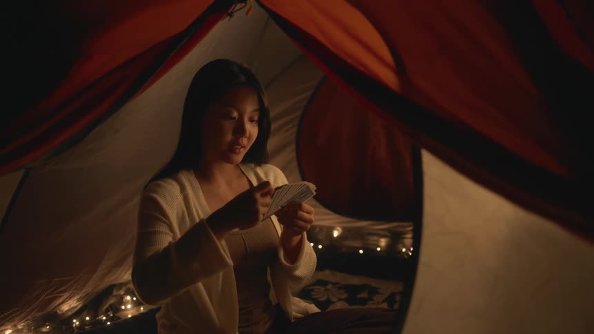 A female is playing a game of cards while camping