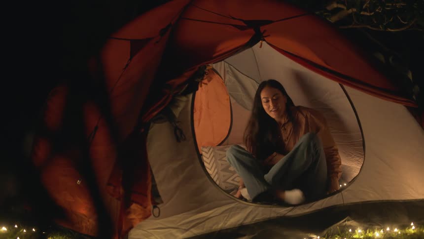 A woman is walking into her tent at night
