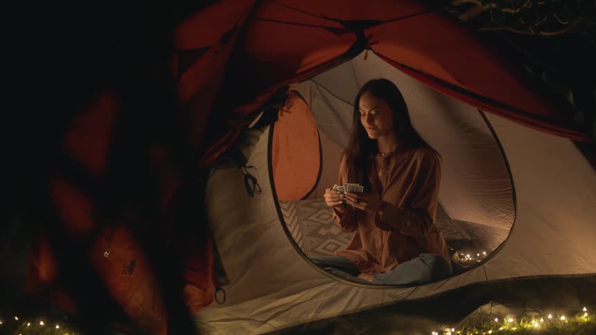 A woman is sitting in a tent and playing a card game