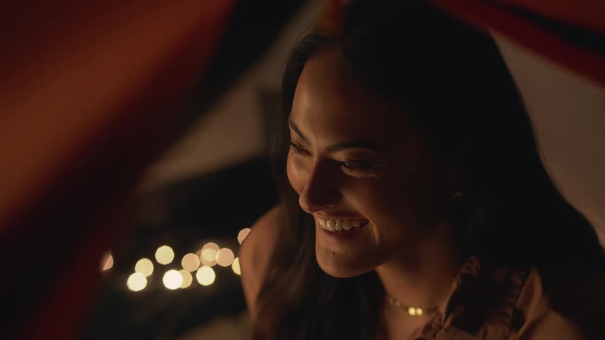 Close up of a girl surrounded by candles on a dimly lit room talking to a friend